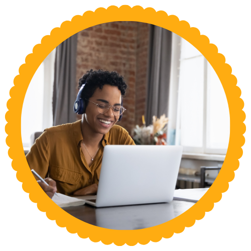 Student Young college student with headphones smiles while looking at laptop computer.